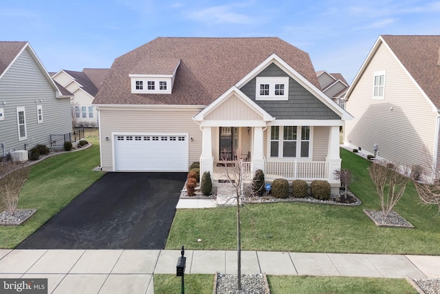 craftsman house featuring a garage, covered porch, a front lawn, and central air condition unit