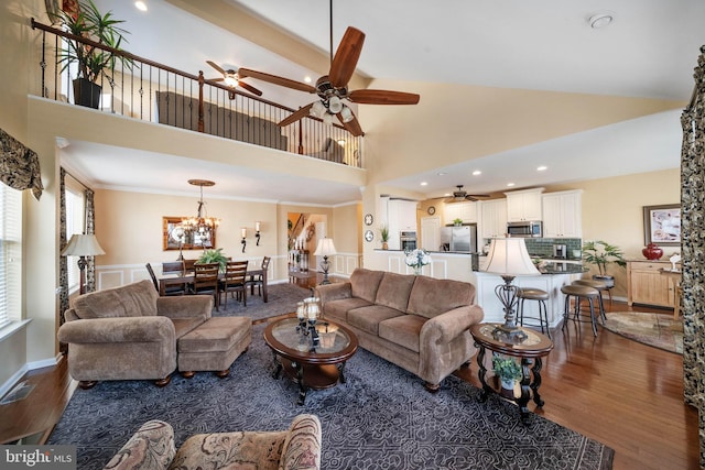 living room featuring crown molding, ceiling fan with notable chandelier, high vaulted ceiling, and dark hardwood / wood-style floors