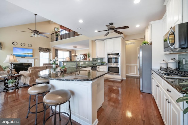 kitchen with stainless steel appliances, white cabinetry, and dark wood-type flooring