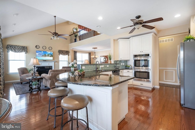 kitchen featuring dark wood-type flooring, sink, dark stone countertops, stainless steel appliances, and white cabinets