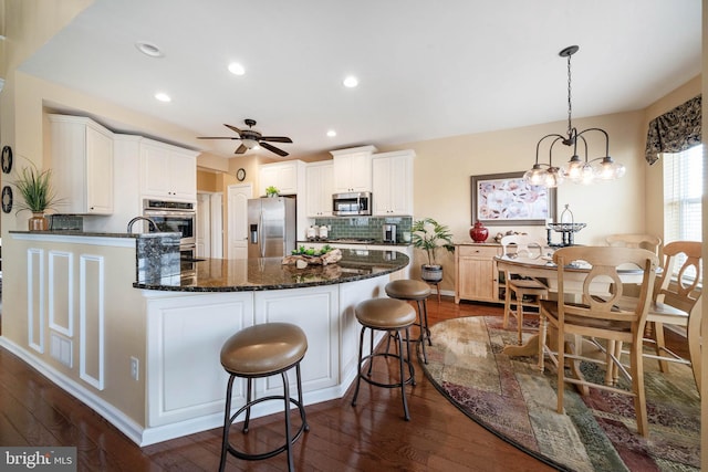 kitchen with appliances with stainless steel finishes, dark hardwood / wood-style floors, decorative light fixtures, white cabinets, and decorative backsplash