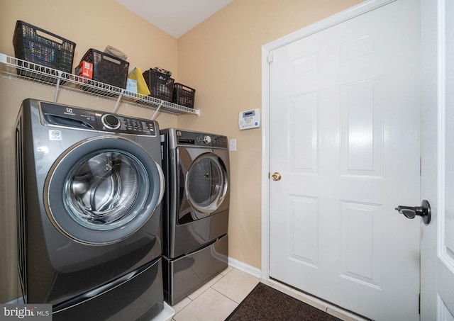 clothes washing area featuring washer and clothes dryer and light tile patterned flooring