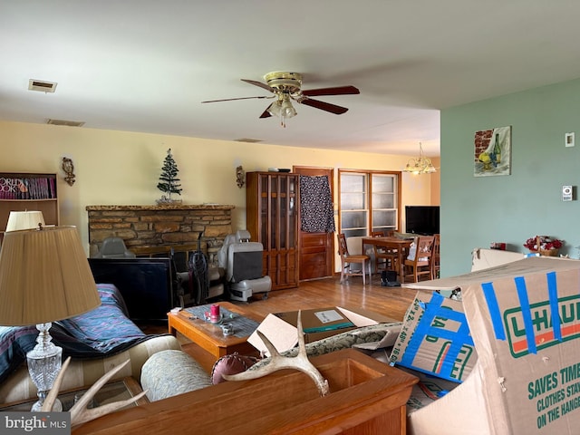 living room featuring wood finished floors, ceiling fan with notable chandelier, and visible vents