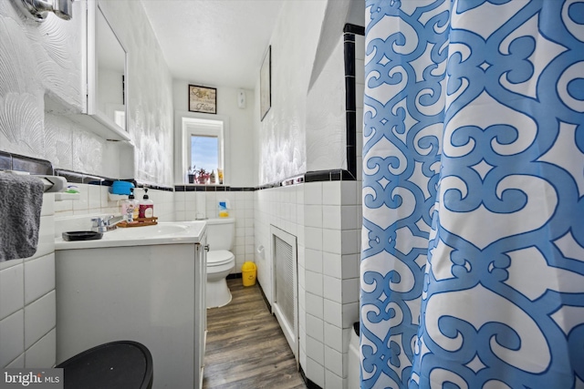 bathroom featuring wood-type flooring, tile walls, vanity, toilet, and a shower with curtain