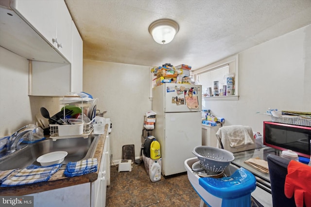 kitchen featuring sink, a textured ceiling, white cabinets, and white refrigerator