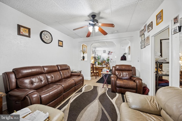 carpeted living room featuring ceiling fan and a drop ceiling