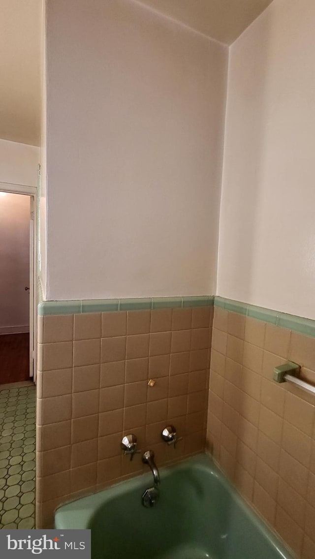 bathroom featuring tile walls and a washtub