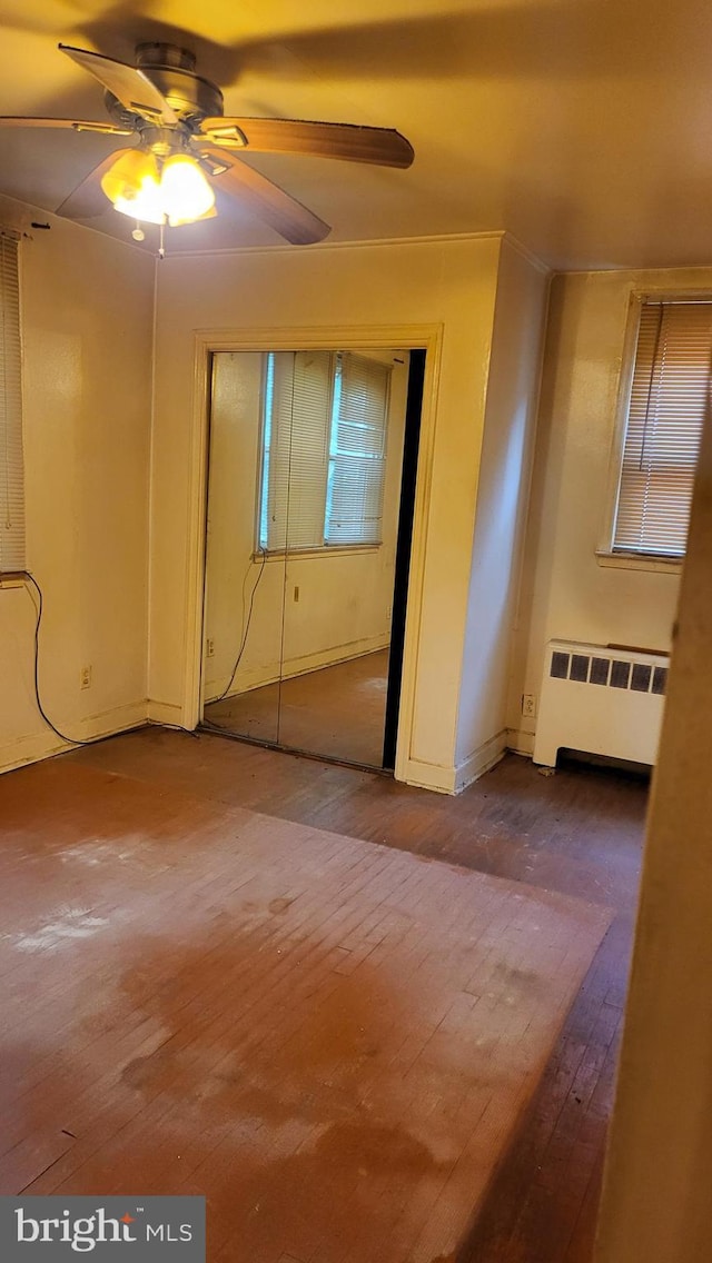 unfurnished room with ceiling fan, radiator heating unit, and wood-type flooring