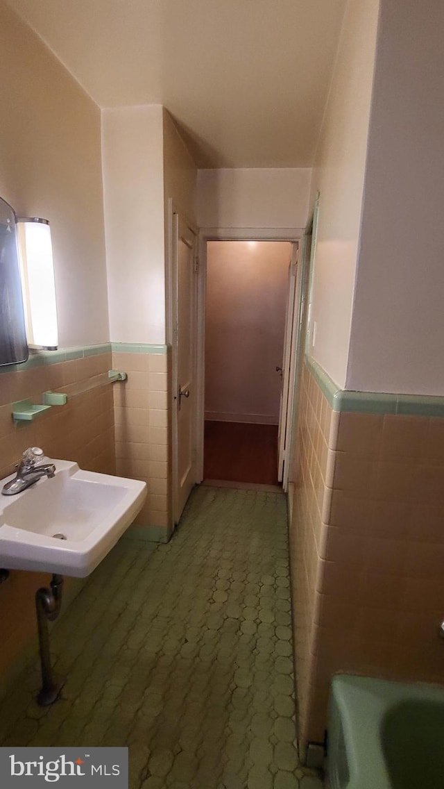 bathroom featuring tile walls, sink, and a bath