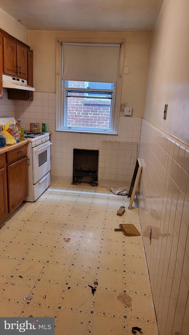 kitchen with tile walls, a fireplace, and gas range gas stove