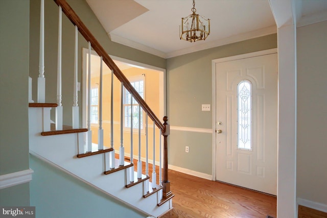 entryway with crown molding, hardwood / wood-style flooring, plenty of natural light, and an inviting chandelier