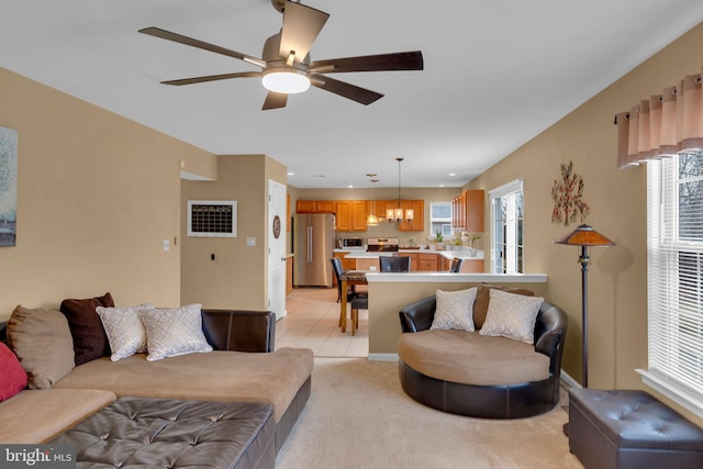 living room with ceiling fan with notable chandelier and light carpet