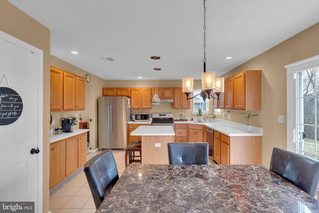 kitchen featuring sink, stainless steel appliances, a kitchen breakfast bar, a kitchen island, and decorative light fixtures