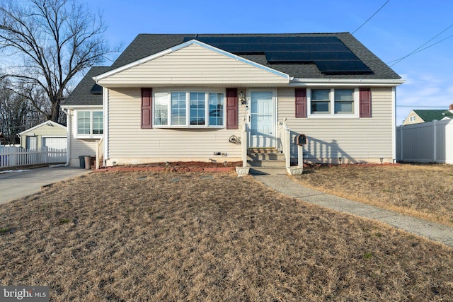 bungalow-style house with a garage, an outbuilding, a front yard, and solar panels