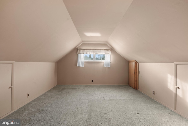 bonus room with light colored carpet and vaulted ceiling