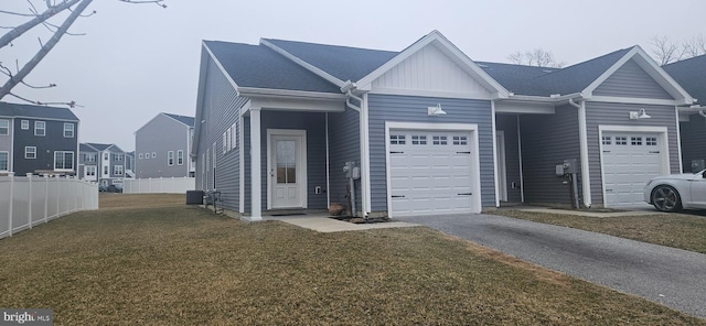 view of front of house with fence, an attached garage, a front lawn, aphalt driveway, and board and batten siding