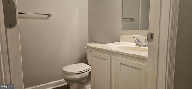 half bathroom featuring toilet, vanity, and baseboards