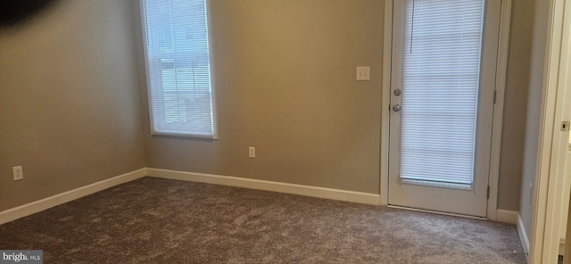 unfurnished room with baseboards and dark carpet