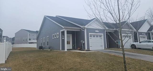 view of front of house with a front lawn, driveway, fence, a residential view, and a garage