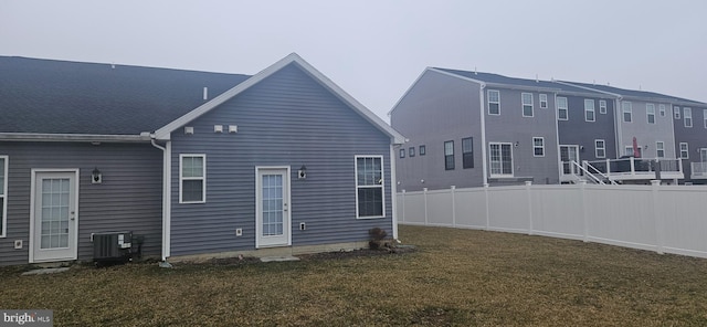 back of house featuring central AC unit, a lawn, and fence