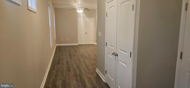 corridor featuring dark wood-type flooring and baseboards