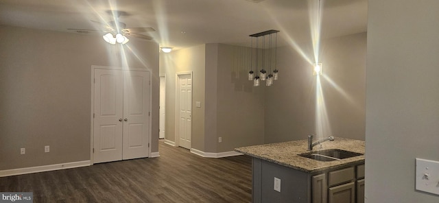 kitchen with a ceiling fan, light stone countertops, baseboards, dark wood finished floors, and a sink