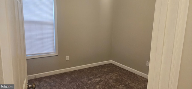 empty room featuring baseboards and dark carpet