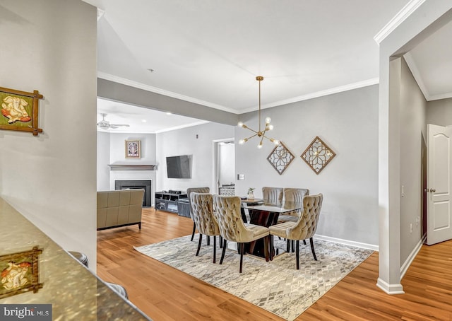 dining area featuring hardwood / wood-style flooring, ornamental molding, and ceiling fan with notable chandelier