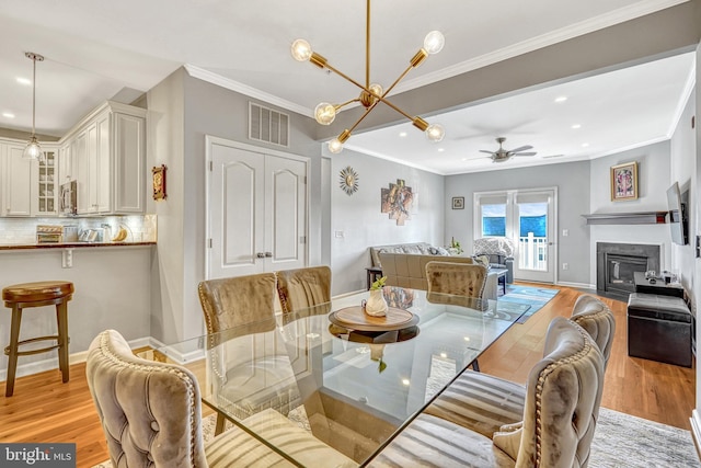 dining area featuring crown molding, ceiling fan with notable chandelier, and light hardwood / wood-style floors