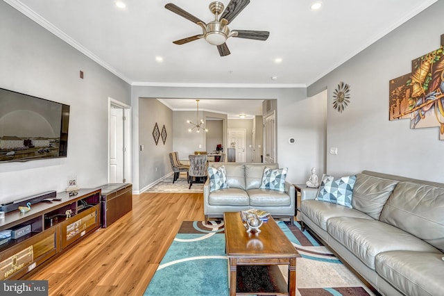 living room featuring ceiling fan with notable chandelier, light hardwood / wood-style flooring, and ornamental molding