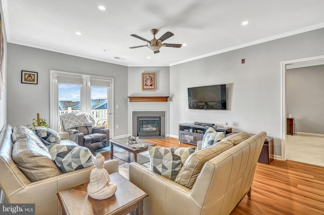 living room featuring ornamental molding, ceiling fan, and light wood-type flooring