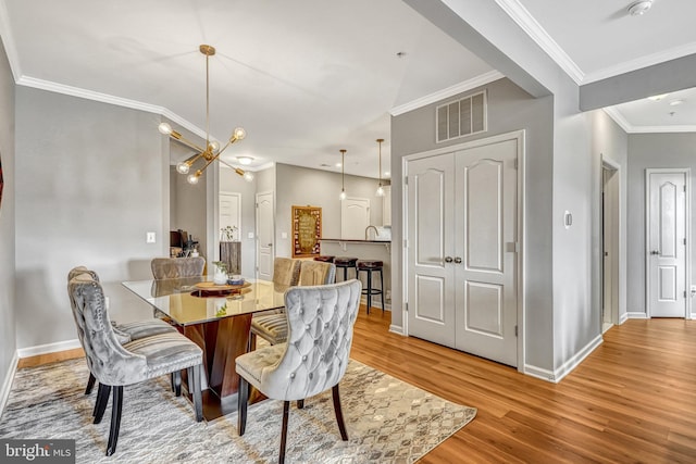 dining area featuring crown molding, a notable chandelier, and light wood-type flooring