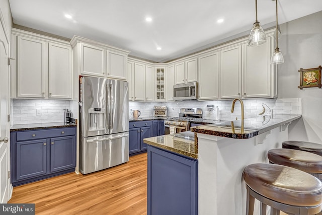 kitchen with pendant lighting, blue cabinetry, a breakfast bar, white cabinetry, and stainless steel appliances