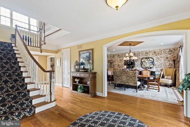 entrance foyer with an inviting chandelier, hardwood / wood-style floors, and ornamental molding