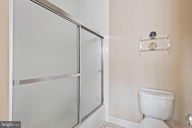 bathroom featuring tile patterned floors, combined bath / shower with glass door, and toilet