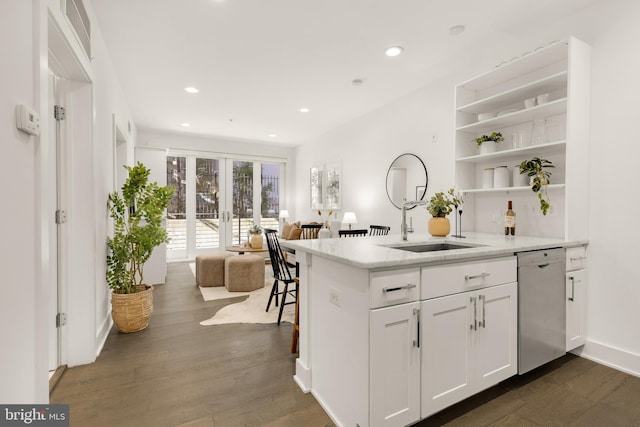 kitchen with white cabinetry, dark wood-type flooring, stainless steel dishwasher, and kitchen peninsula