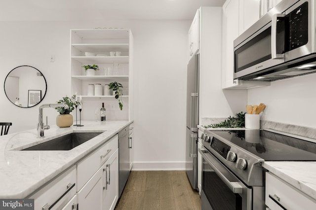 kitchen with light stone counters, appliances with stainless steel finishes, sink, and white cabinets