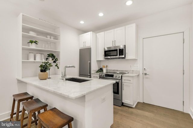 kitchen featuring white cabinetry, appliances with stainless steel finishes, sink, and a kitchen breakfast bar