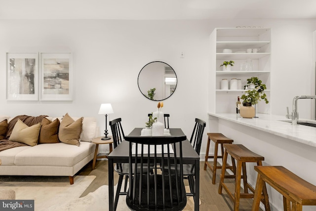 dining room with sink, built in features, and light wood-type flooring