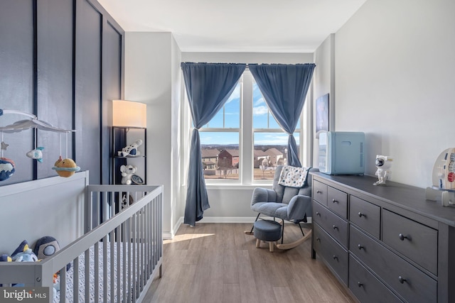 bedroom featuring a nursery area and light wood-type flooring