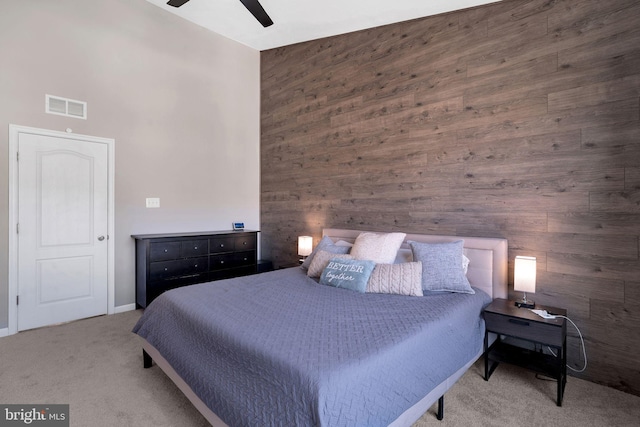 bedroom with ceiling fan, a towering ceiling, carpet floors, and wood walls