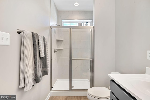 bathroom featuring walk in shower, vanity, toilet, and hardwood / wood-style flooring