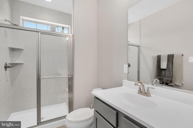 bathroom featuring vanity, toilet, and a shower with shower door