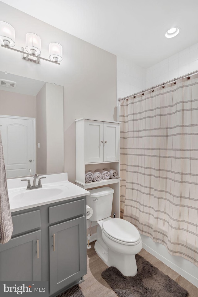 full bathroom with shower / tub combo with curtain, vanity, toilet, and hardwood / wood-style floors