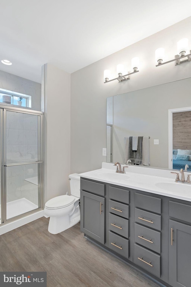 bathroom featuring hardwood / wood-style flooring, vanity, a shower with door, and toilet