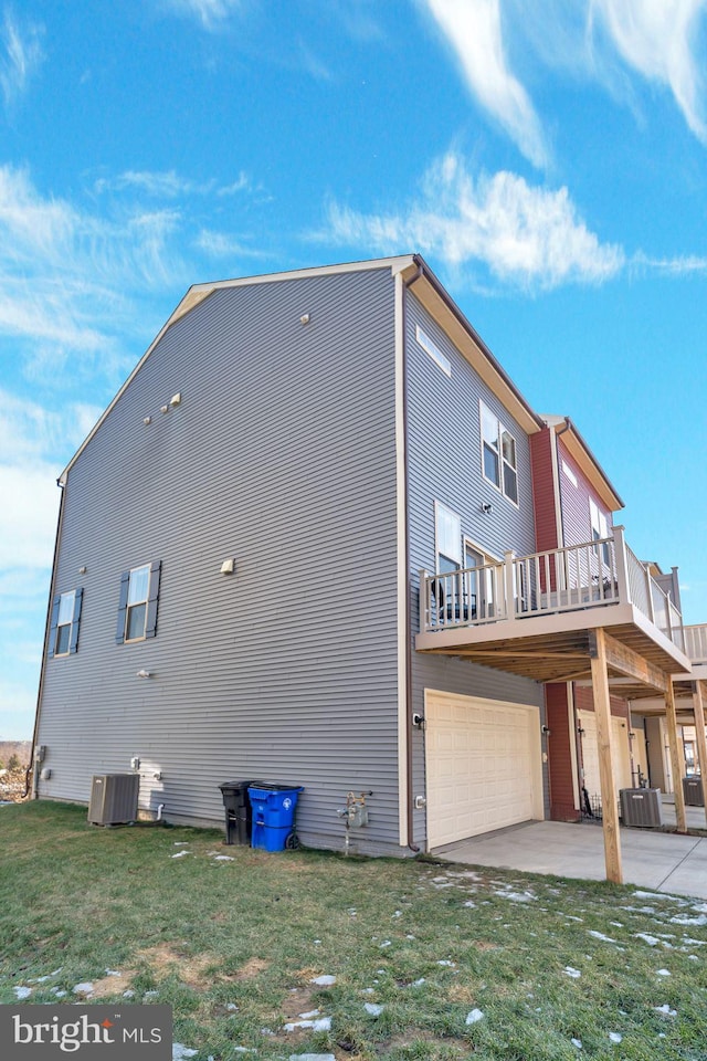 view of side of property with central AC unit, a garage, a lawn, and a patio