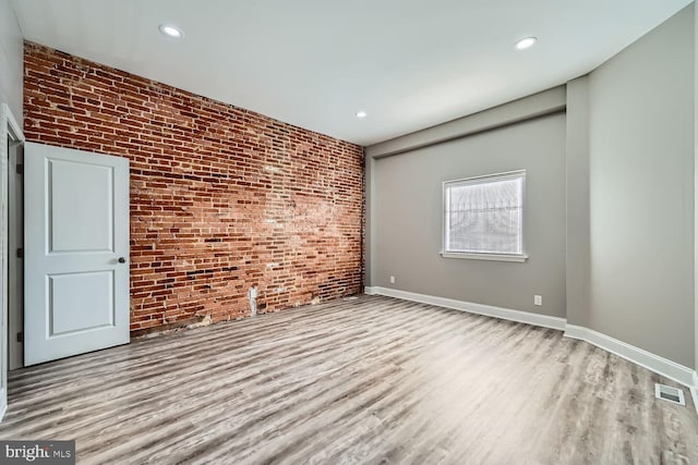 empty room featuring light hardwood / wood-style floors and brick wall