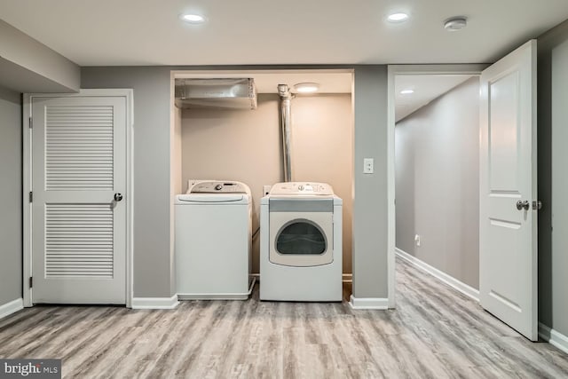 laundry area featuring separate washer and dryer and light hardwood / wood-style floors