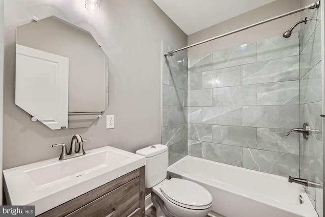 full bathroom featuring vanity, tiled shower / bath combo, and toilet