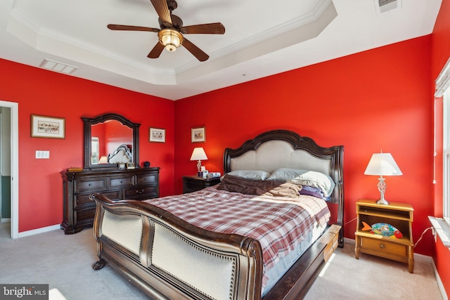 carpeted bedroom with crown molding, a tray ceiling, visible vents, and baseboards